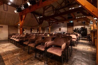 Uitzicht op een sfeervolle zaal met rijen zitplaatsen en houten elementen in een gezellige ambiance.